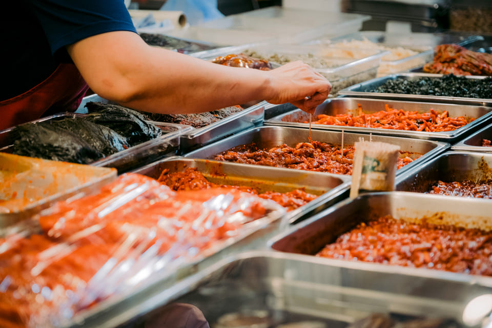 Hands reaching for food at a buffet.